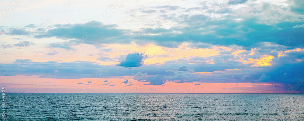 Beautiful colorful evening sunset sky over sea in blue and pink tones.