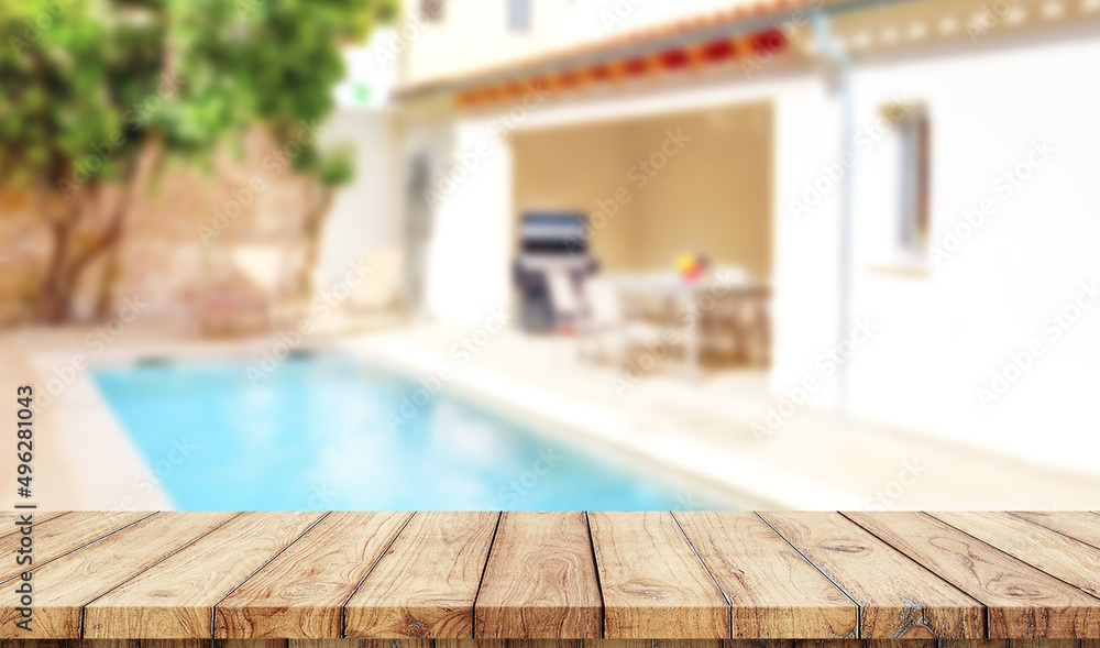 Empty wooden table with blurred luxury garden with swimming pool on background