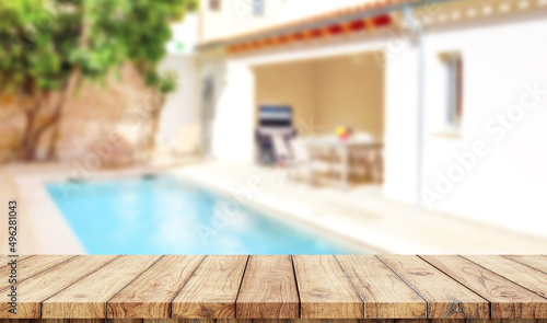 Empty wooden table with blurred luxury garden with swimming pool on background