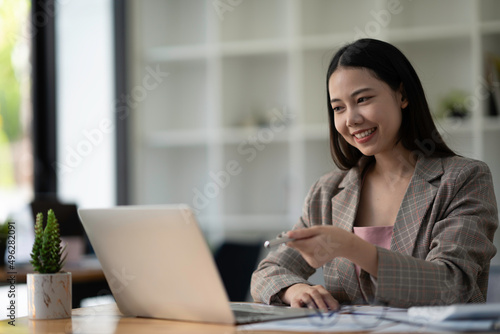 Portrait of freelance smart business women casual wear using tablet working in workplace in living room at home. Happy young Asian girl relax sitting on desk search and do job in internet.