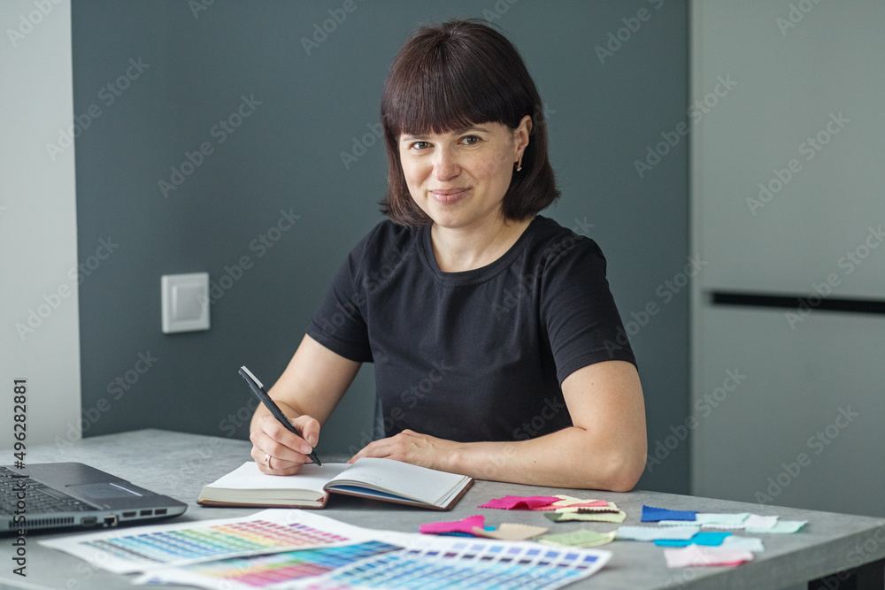 Successful woman plans work schedule, writes in notebook, sitting at workplace with laptop. Successful woman plans work schedule, writes in notebook, sitting at workplace with laptop.