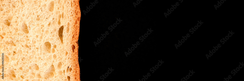 slice of white bread close up isolated on a black background. rough textured surface chopped piece loaf of natural organic food with holes. top view. abstract concept of the planet and space. banner slice of white bread close up isolated on a black background. rough textured surface chopped piece loaf of natural organic food with holes. top view. abstract concept of the planet and space. banner
