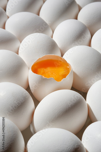 Foto Row of white eggs and single broken egg with a yolk