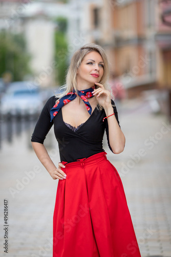 Urban portrait of a beautiful sexy young blonde in a red skirt and with a deep neckline. High quality photo