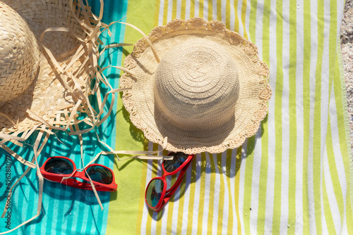 High angle view of sun hats and sunglasses on towel at beach during sunny day