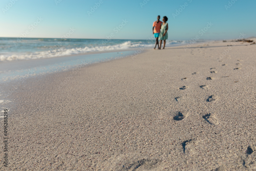 Footprints on sand at beach with african american couple walking during sunny day Footprints on sand at beach with african american couple walking during sunny day