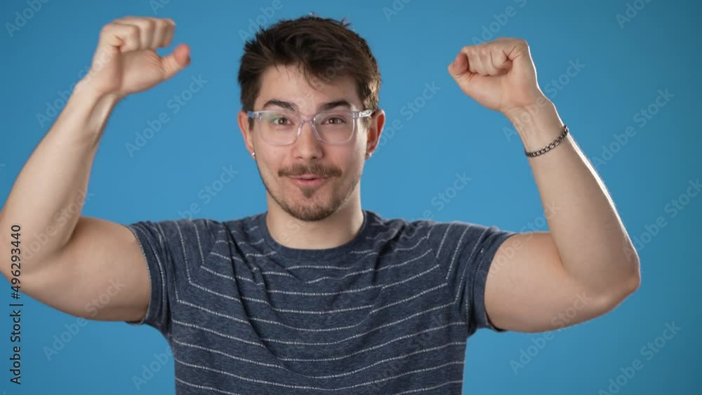Shocked amazed say wow doing winner gesture put hands up young man 20s posing isolated on blue background studio. People lifestyle concept. Shocked amazed say wow doing winner gesture put hands up young man 20s posing isolated on blue background studio. People lifestyle concept.