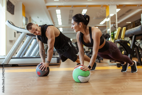 Athletic man and woman are training together with medicine ball in modern gym. Healthy lifestyle