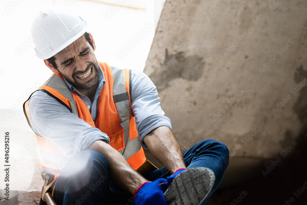 Handsome engineer injured his ankle when he stepped on a nail while inspecting a house project. Concept of occupational safety and occupational accident insurance.