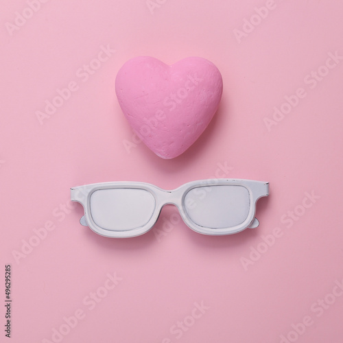 Sunglasses with heart on pink background. Love concept. Top view