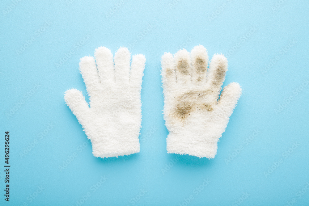 Clean and dirty child white warm gloves on light blue table background. Pastel color. Compare two objects. Closeup. Top down view. Clean and dirty child white warm gloves on light blue table background. Pastel color. Compare two objects. Closeup. Top down view.