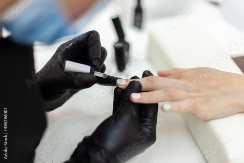 Manicurist paints with nail polish the nails of a woman s clint in nail salon. The working process