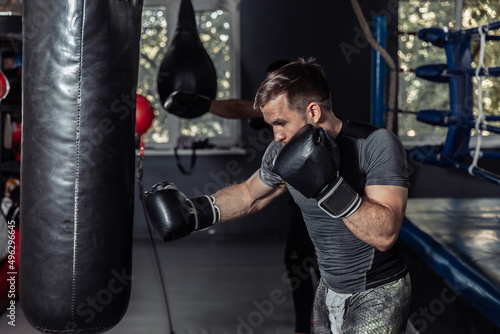 Athlete boxer trains punches in boxing gloves with a punching bag © splitov27