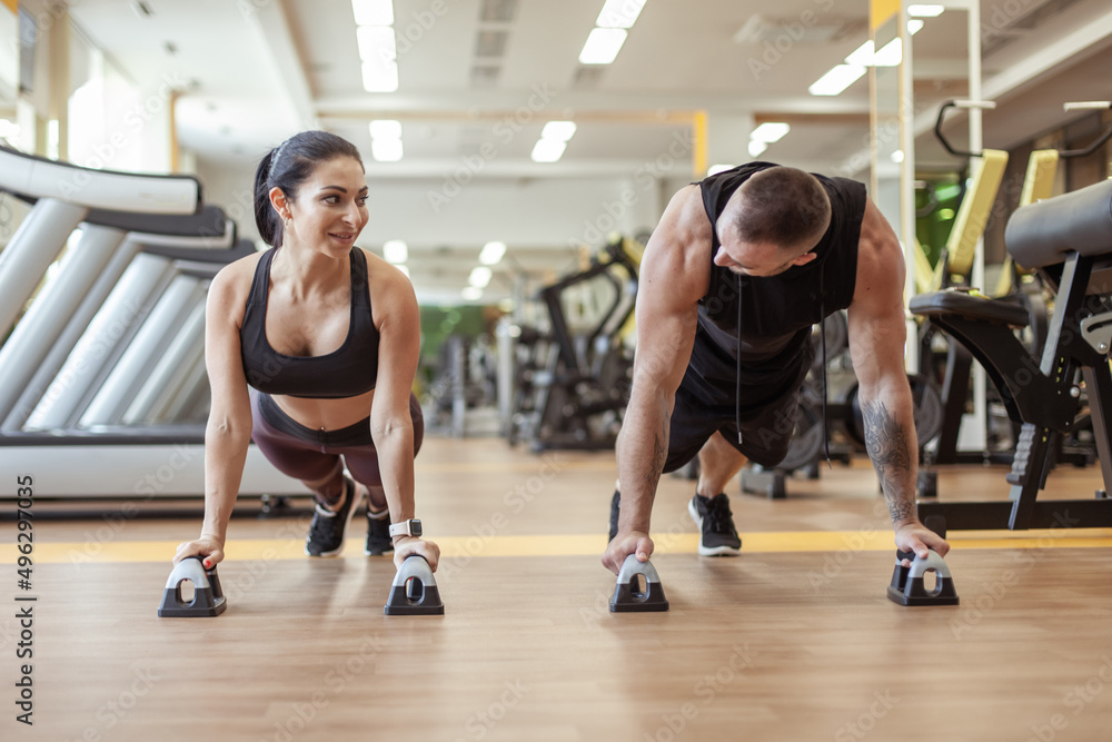 Workout together. Athletic man and woman are training doing push-ups in the gym. Healthy lifestyle