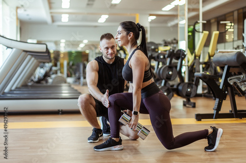 Young fit woman training muscles with personal trainer man in the gym