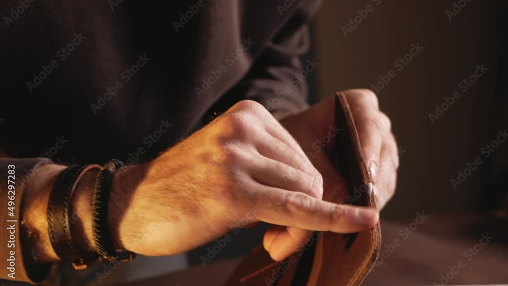 tanner makes genuine leather wallet, professional craftsman, closeup, indoor, authentic, business. Handiwork. lubricates edges with cream tanner makes genuine leather wallet, professional craftsman, closeup, indoor, authentic, business. Handiwork. lubricates edges with cream