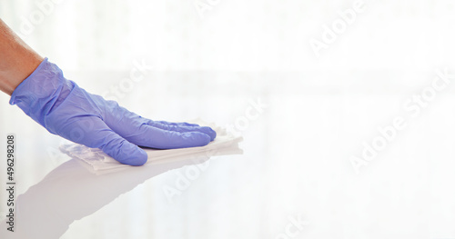 Surface disinfecting home cleaning with sanitizing antibacterial wipes protection against COVID-19 spreading wearing medical blue gloves. Sanitize surfaces prevention in hospitals and public spaces
