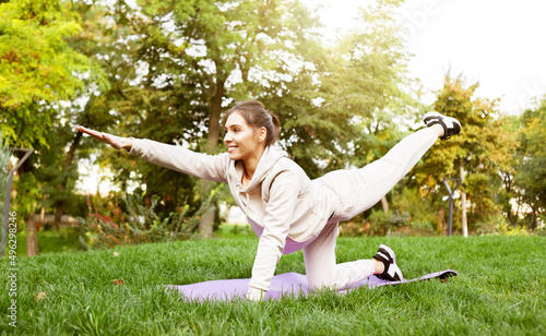 Fit woman doing yoga or pilates exercises on the mat outdoor. Chakravakasana pose photo