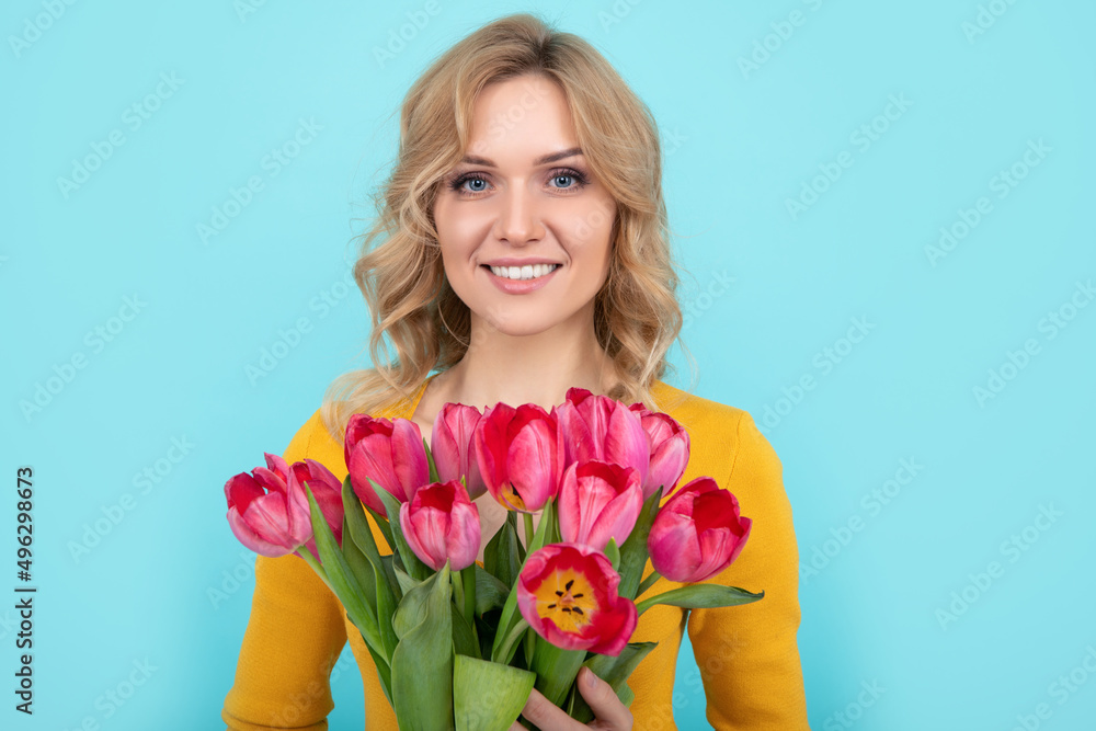 happy young woman with spring tulip flowers on blue background. march 8
