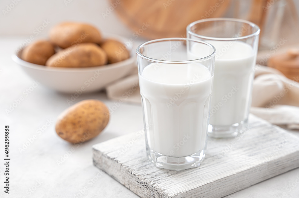 Vegetable potato milk on a white background with raw potatoes. An alternative to cow's milk. Side view, copy space. Vegetable potato milk on a white background with raw potatoes. An alternative to cow's milk. Side view, copy space.