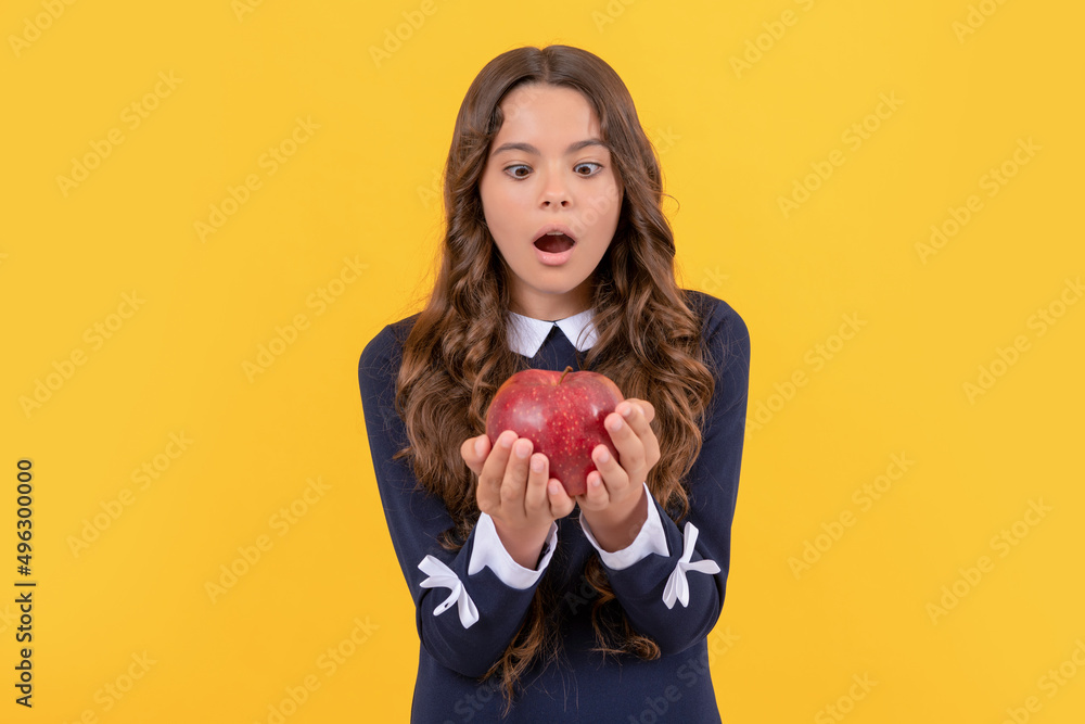 shocked child looking at red vitamin apple for lunch on yellow background, detox shocked child looking at red vitamin apple for lunch on yellow background, detox