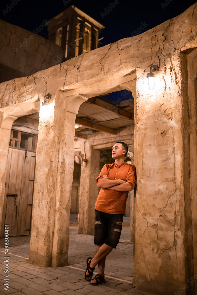 Man tourist walking in Al Seef Meraas Dubai - old historical district with traditional Arabic architecture