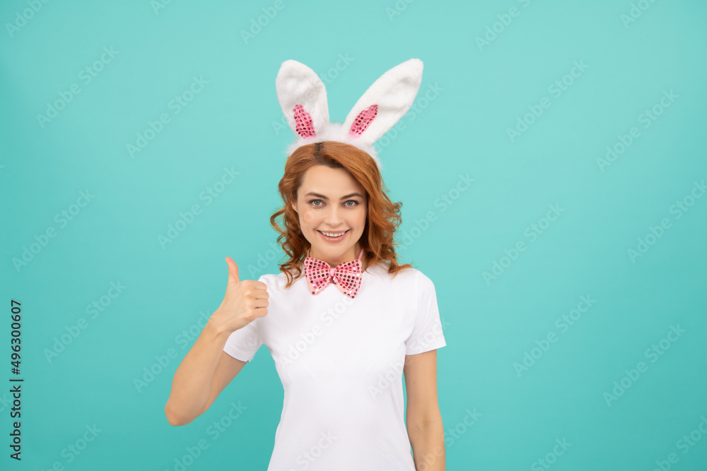 happy easter woman with bunny ears on blue background. thumb up