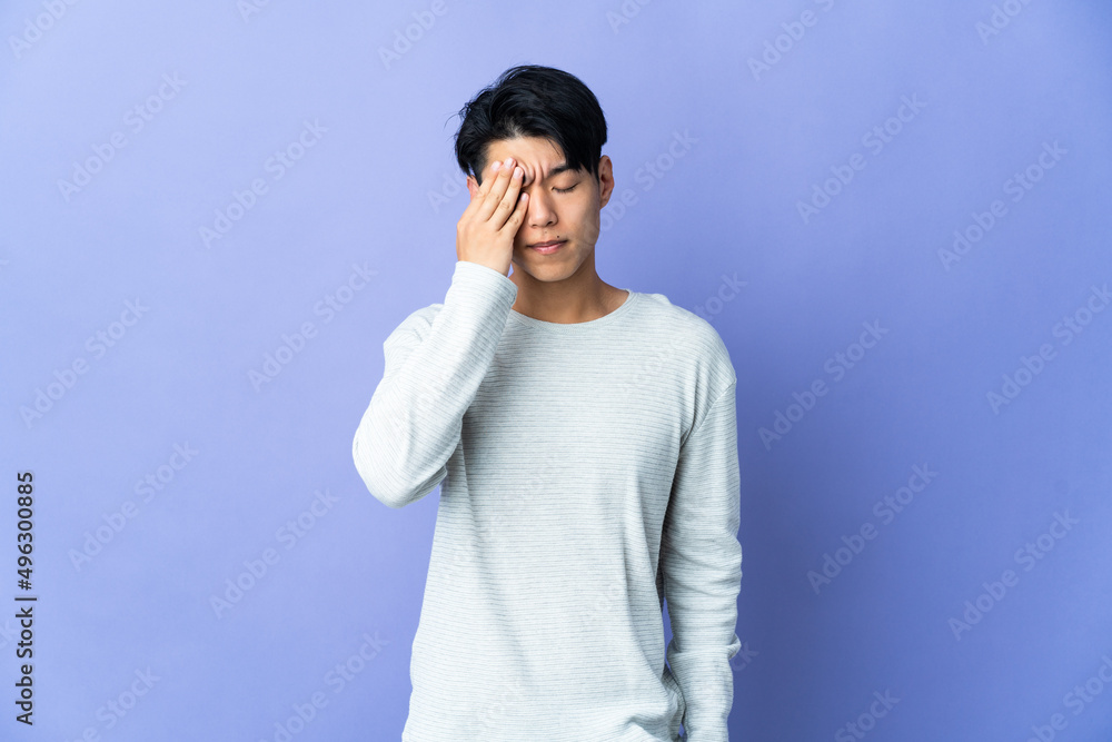 Young Chinese man isolated on purple background with headache Young Chinese man isolated on purple background with headache
