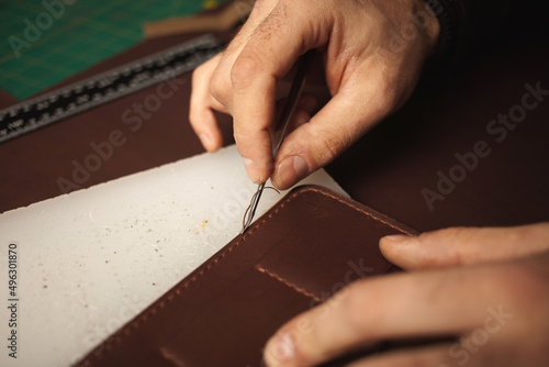 tanner makes genuine leather wallet, professional craftsman, closeup, indoor, authentic, business. Handiwork.
