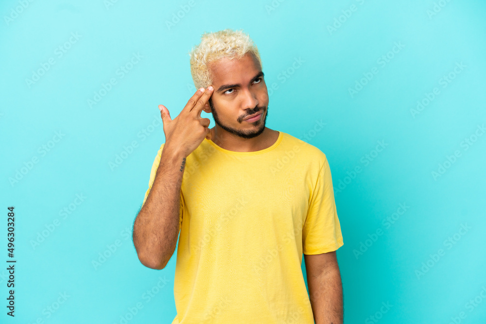 Young Colombian handsome man isolated on blue background with problems making suicide gesture Young Colombian handsome man isolated on blue background with problems making suicide gesture