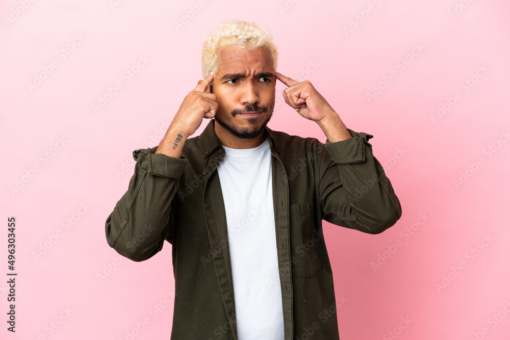 Young Colombian handsome man isolated on pink background having doubts and thinking Young Colombian handsome man isolated on pink background having doubts and thinking