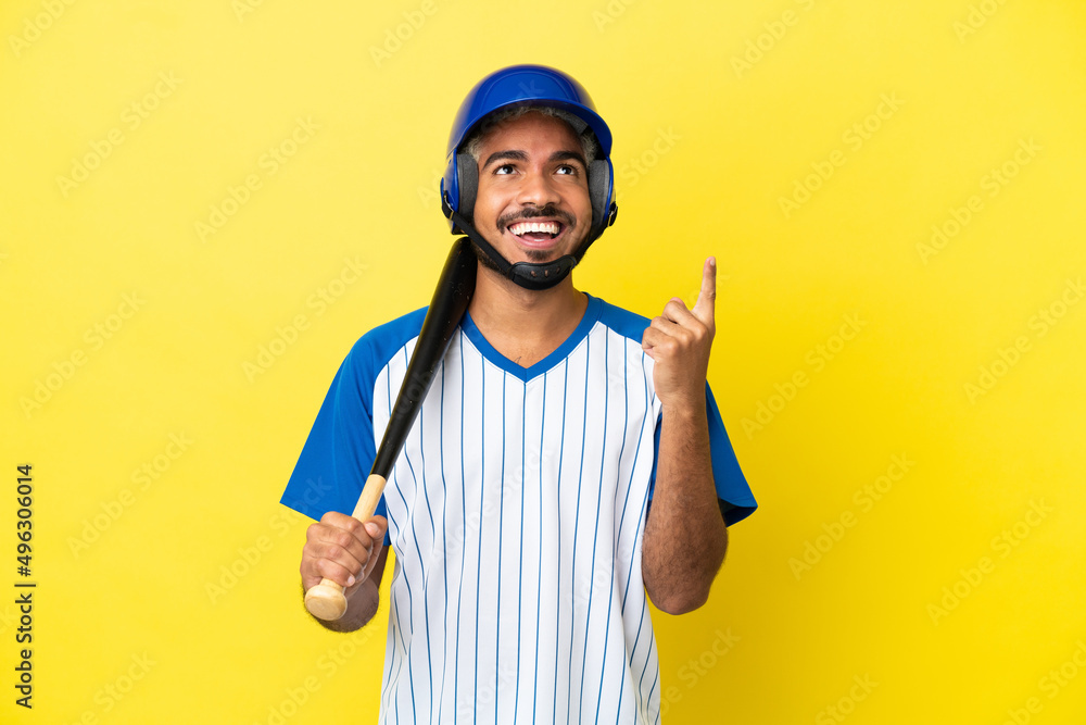 Young Colombian latin man playing baseball isolated on yellow background pointing up a great idea