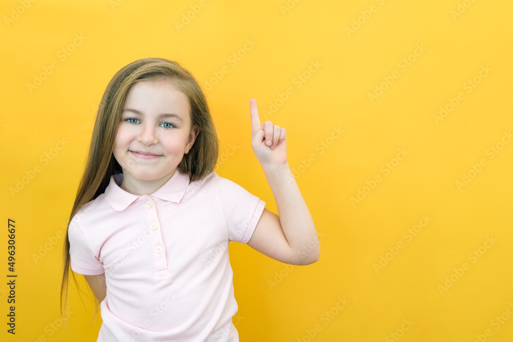 Wow, look, advertise here! Portrait of an astonished cute girl pointing at an empty space in the background, a preschooler shows a copy space for an advertisement