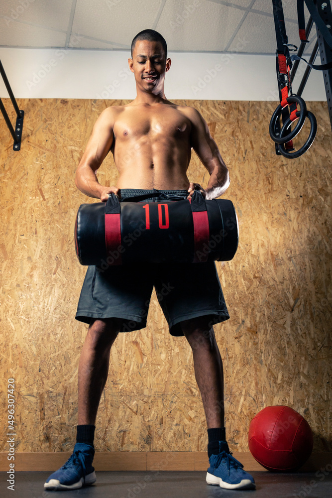 Shirtless sportsman lifting heavy sandbag Stock Photo Adobe Stock
