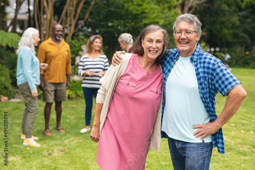 Portrait of happy caucasian senior couple with multiracial friends in background