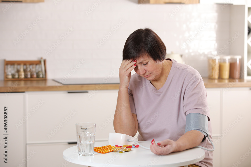 sick older woman take care for health, using sphygmomanometer for measure blood pressure, pulse and heart rate by self and takes medication at home