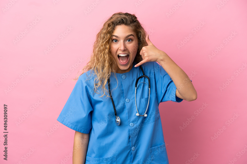 Young surgeon doctor woman isolated on pink background making phone gesture. Call me back sign Young surgeon doctor woman isolated on pink background making phone gesture. Call me back sign
