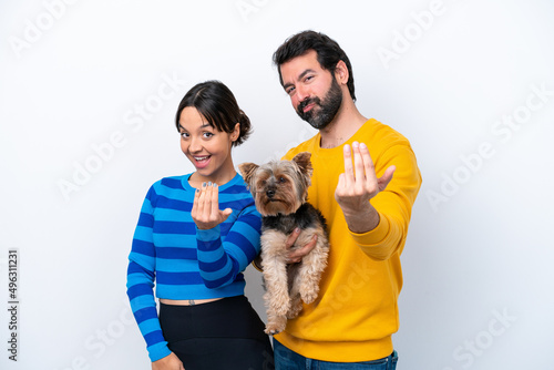 Young hispanic woman holding a dog isolated on white background inviting to come with hand
