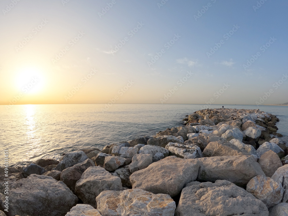 Seascape with Malaga and sunrise sunlight. Sandy beach of the Mediterranean Sea and walking stone pier in Playa de la Caleta, Spain