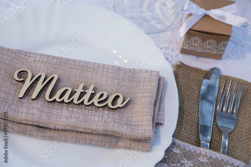 Dettaglio di piatto bianco con la scritta Matteo su un tavolo apparecchiato con eleganza photo