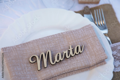 Dettaglio di piatto bianco con la scritta Marta su un tavolo apparecchiato con eleganza photo