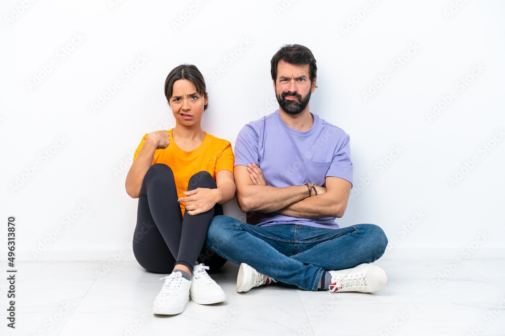 Young caucasian couple sitting on the floor isolated on white background annoyed angry in furious gesture Young caucasian couple sitting on the floor isolated on white background annoyed angry in furious gesture
