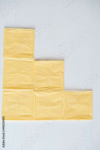 Separately packed cheese slices on a white wooden table background