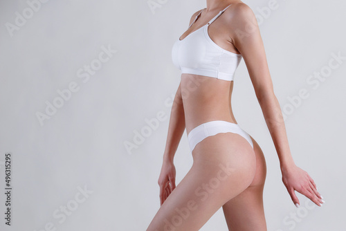 Close up shot of unrecognizable fit woman in lingerie isolated on white background. Cropped shot of lower half of slim attractive female's body in white underwear. Copy space for text.