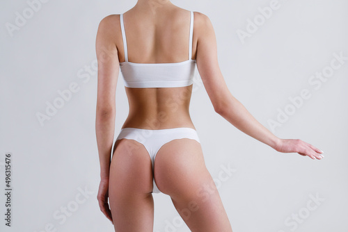 Close up shot of unrecognizable fit woman in lingerie isolated on white background. Cropped shot of lower half of slim attractive female's body in white underwear. Copy space for text. photo
