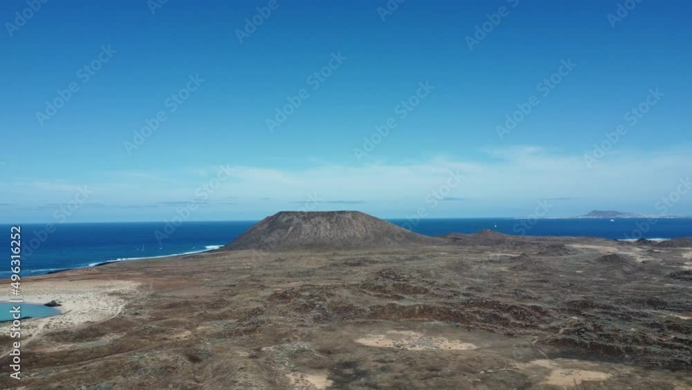 An aerial view of the Island of Wolves in Spain showing a beautiful clear blue sky as you fly over rugged terrain towards a small mountain. An aerial view of the Island of Wolves in Spain showing a beautiful clear blue sky as you fly over rugged terrain towards a small mountain.