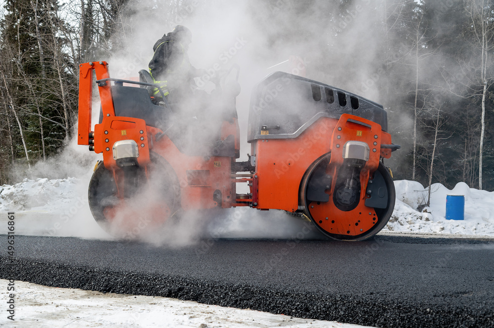 Roller compactor and asphalting in winter on a road Roller compactor and asphalting in winter on a road