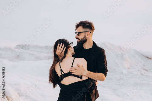 Stylish couple walking and hugging walking on a background of white mountains. Lovely hipster couple enjoying time together. The concept of youth, love and lifestyle. Springtime.
