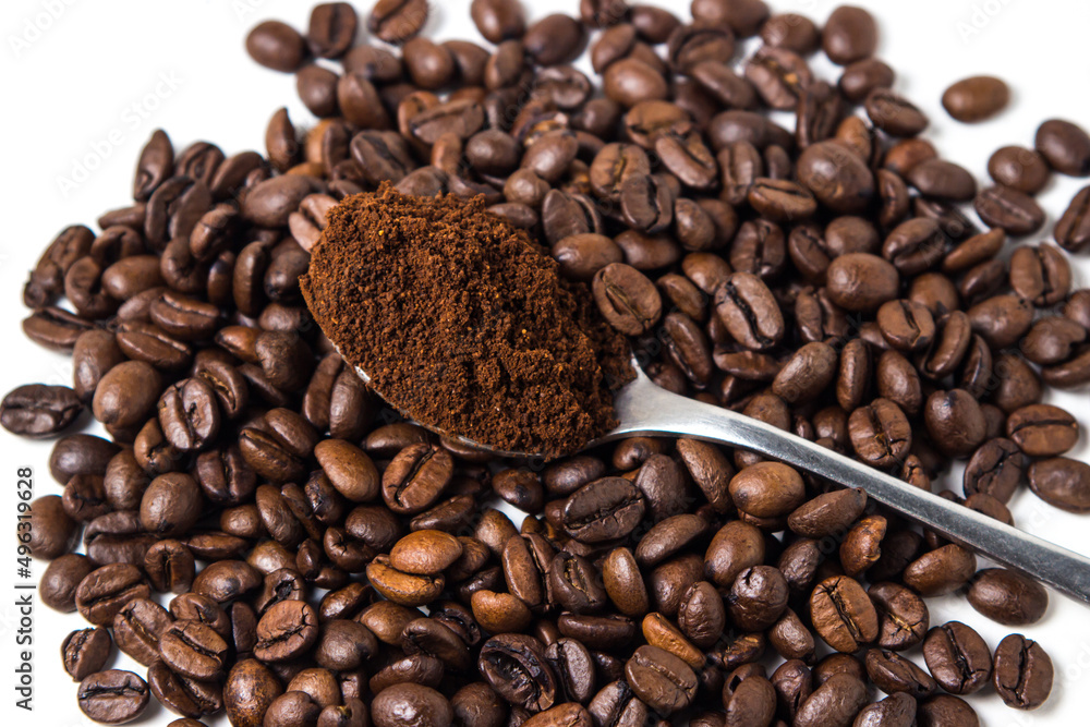 A spoon of ground coffee next to coffee beans on a white background. Roasted coffee beans. tonic drink A spoon of ground coffee next to coffee beans on a white background. Roasted coffee beans. tonic drink