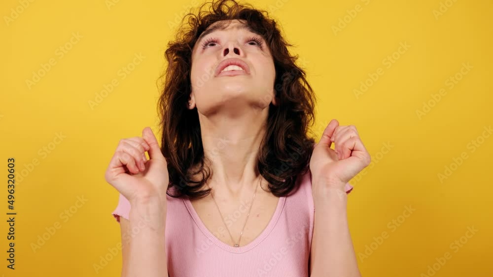 Portrait of lady crossing fingers on hands, make a wish and her wish didn't come true. Sad girl. Attractive young girl on yellow background. Portrait of lady crossing fingers on hands, make a wish and her wish didn't come true. Sad girl. Attractive young girl on yellow background.